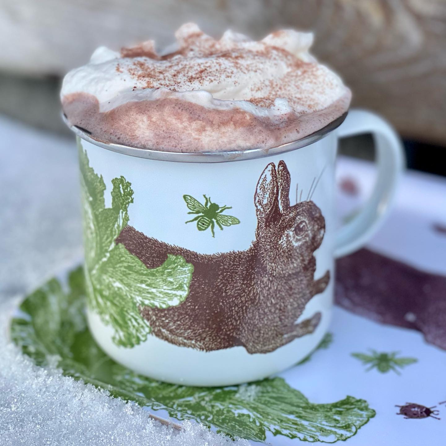 Emaljmugg med hare fylld med varm choklad med vispgrädde
